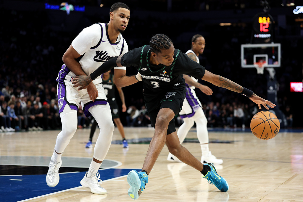 Minnesota Timberwolves forward Jaden McDaniels, front right, controls the ball as Sacramento Kings forward Keegan Murray, left, defends during the first half of an NBA basketball game Sunday, Dec. 14, 2025, in Minneapolis. (AP Photo/Matt Krohn)