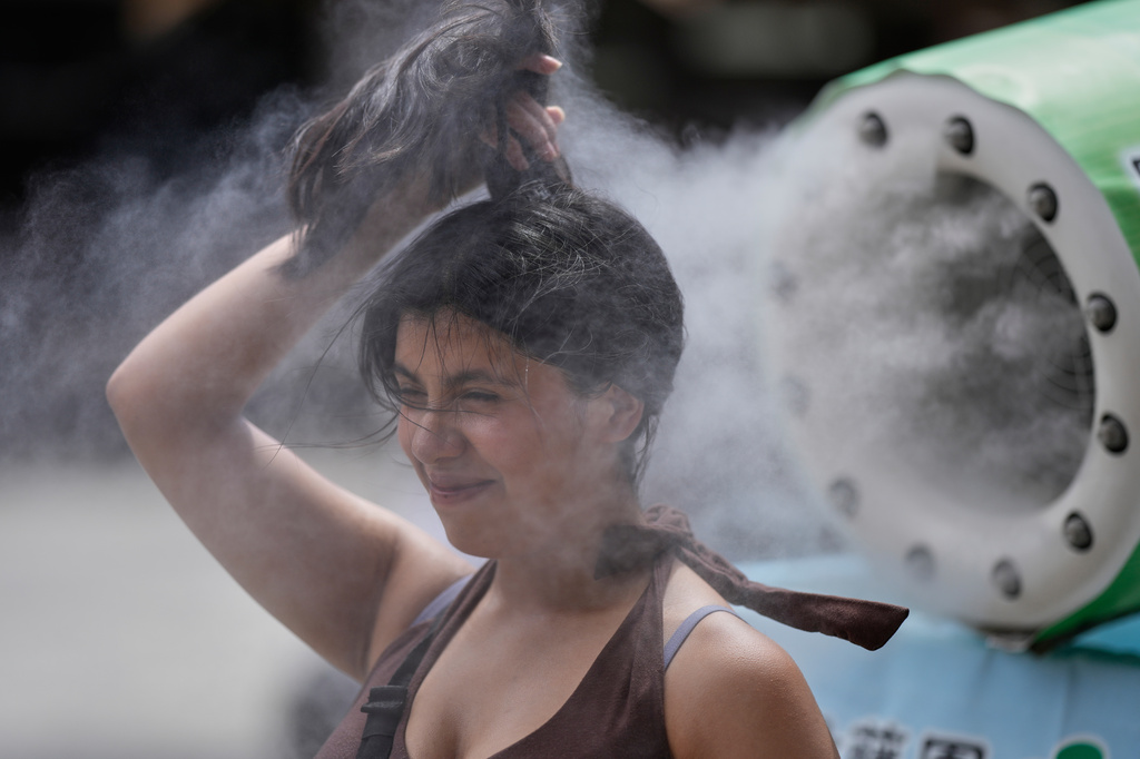 A person cools off at a cooling mist spot on a hot and sunny day at the Sensoji Buddhist temple in Tokyo's Asakusa district, Friday, Aug. 7, 2026. (AP Photo/Eugene Hoshiko)
