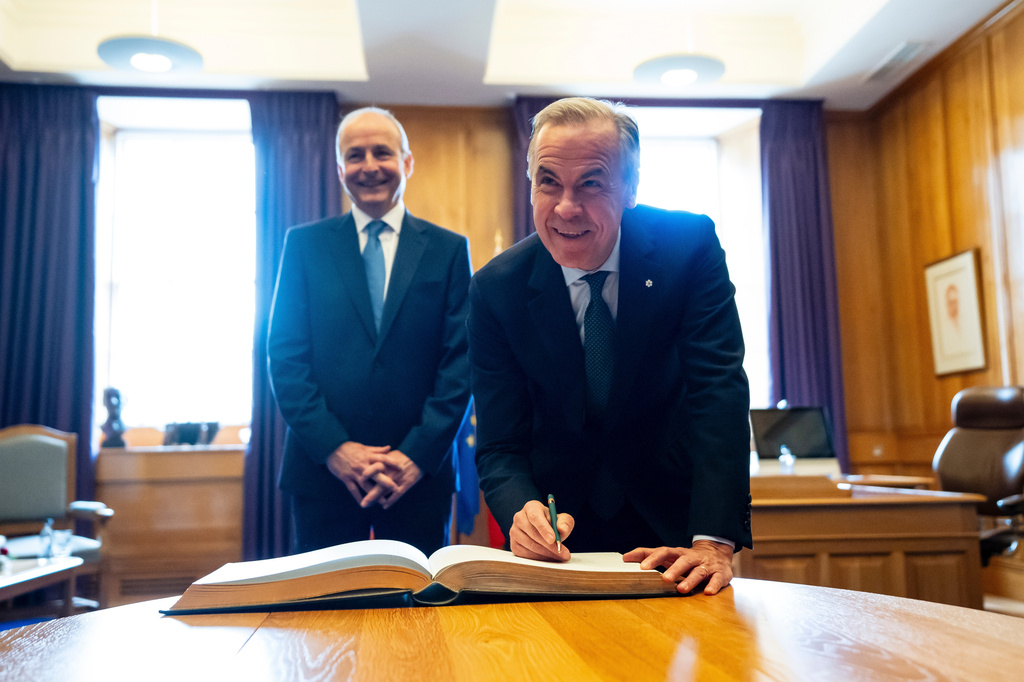 Prime Minister Mark Carney signs the Guest Book as Micheal Martin, Ireland's head of government looks on, at the Government Buildings in Dublin, on Saturday, June 13, 2026. (Christopher Katsarov /The Canadian Press via AP)