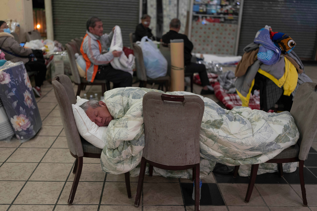 A man rests on a makeshift bed made up of chairs at a nearby shopping mall where residents are taking shelter in the aftermath of the fire at Wang Fuk Court, a residential estate in the Tai Po district of Hong Kong's New Territories, Thursday, Nov. 27 2025. (AP Photo/Ng Han Guan)