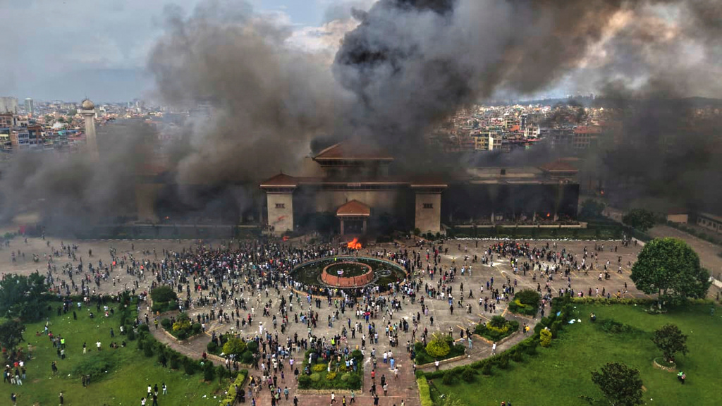 Protesters celebrate at the Singha Durbar, the seat of Nepal's government's various ministries and offices after it was set on fire during a protest against social media ban and corruption in Kathmandu, Nepal, Tuesday, Sept. 9, 2025. (AP Photo/Prakash Timalsina)
