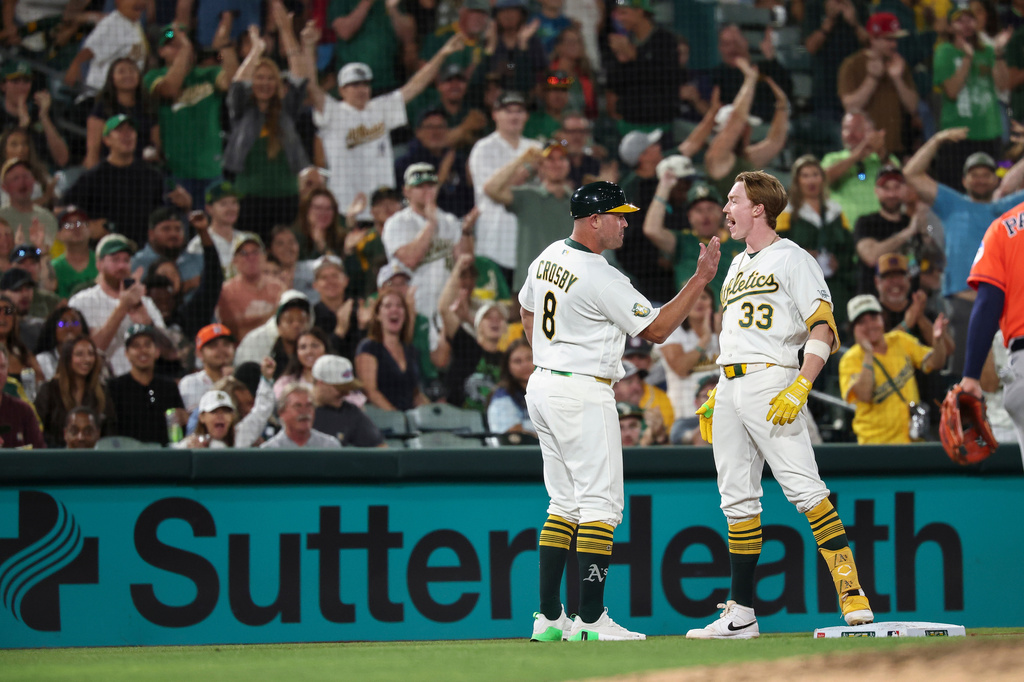 Athletics third base coach Bobby Crosby (8) congratulates Henry Bolte (33) after Bolte hit a two-RBI triple during the sixth inning of a baseball game against the Houston Astros, Friday, Sept. 25, 2026, in West Sacramento, Calif. (AP Photo/Sara Nevis)