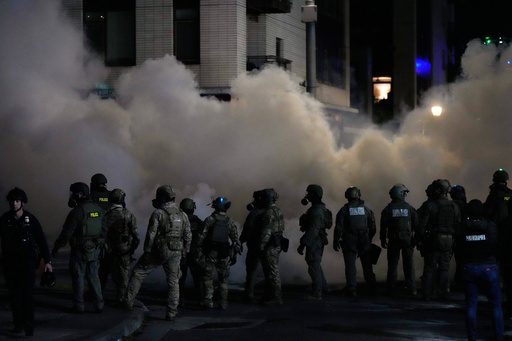 Law enforcement officers stand in tear gas outside a U.S. Immigration and Customs Enforcement facility during a protest on Saturday, Oct. 4, 2025, in Portland, Ore. (AP Photo/Jenny Kane) Law enforcement officers stand in tear gas outside a U.S. Immigration and Customs Enforcement facility during a protest on Saturday, Oct. 4, 2025, in Portland, Ore. (AP Photo/Jenny Kane)