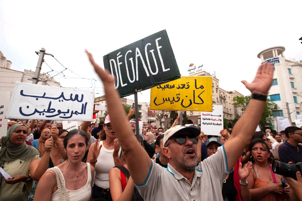Protesters hold signs with messages that read: "Free the prisoners, No one is happy except President Saied and Where is development? Where is freedom? You have destroyed our purchasing power", during a demonstration against President Kais Saied in downtown Tunis, Tunisia, Saturday, July 25, 2026. (AP Photo/Ons Abid)