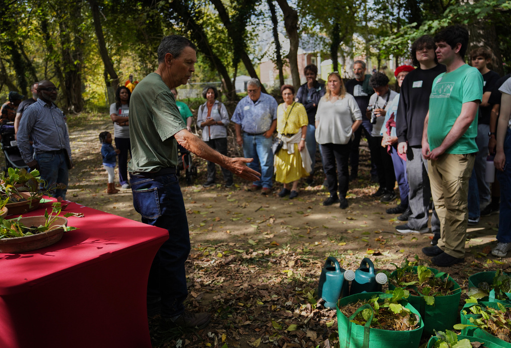 Visitors learn about fall crops like lettuce and kale while on a walking tour of Collins Avenue during the Baltimore Gift Economy's third annual "Finding Home" gathering, Sunday, Oct. 19, 2025, in Baltimore. (AP Photo/Jessie Wardarski)