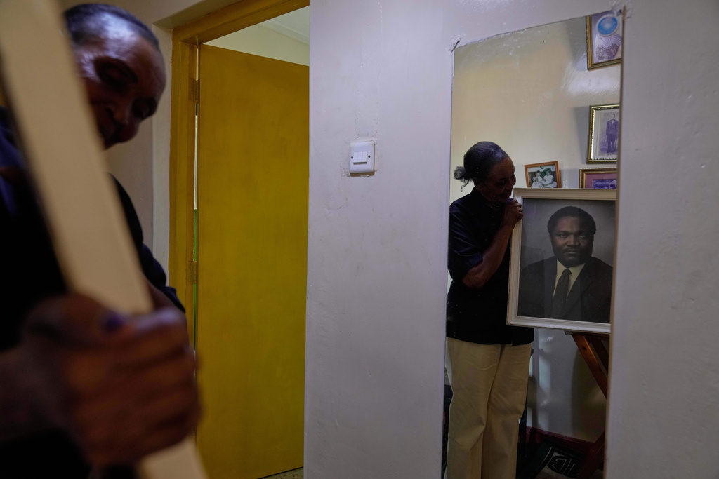 Widow Marie Owino, 87 years old, a former teacher, holds a portrait of her late husband at her home in Siaya, Kenya, Thursday, Nov. 27, 2025. (AP Photo/Brian Inganga)