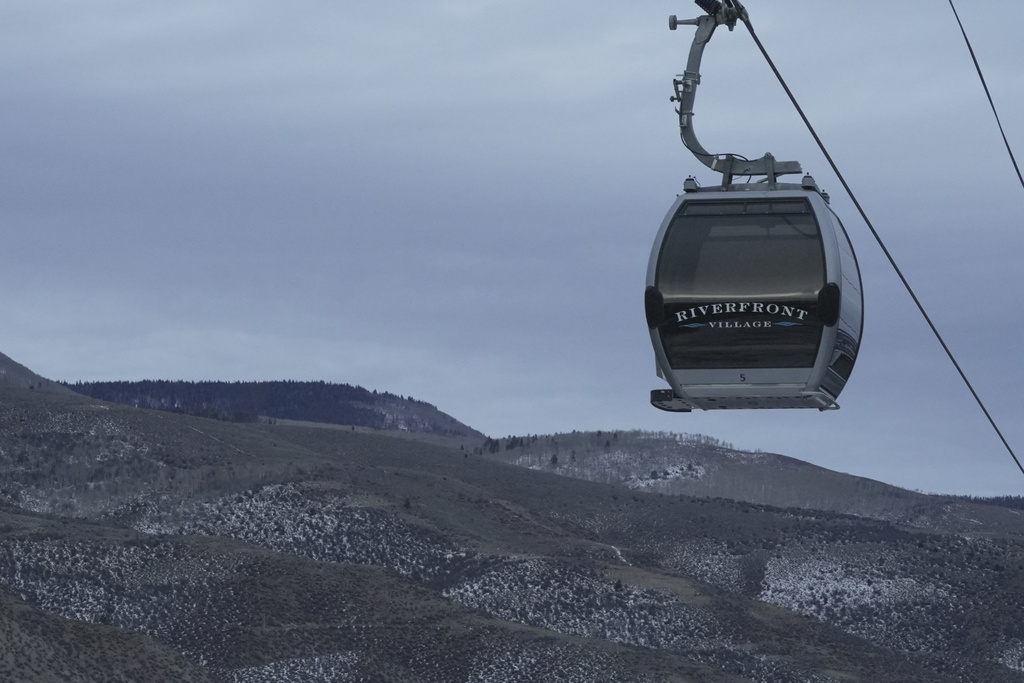 A gondola hangs in front of snow-scarce mountains Thursday, Dec. 18, 2025, in Avon, Colo. (AP Photo/Brittany Peterson)
