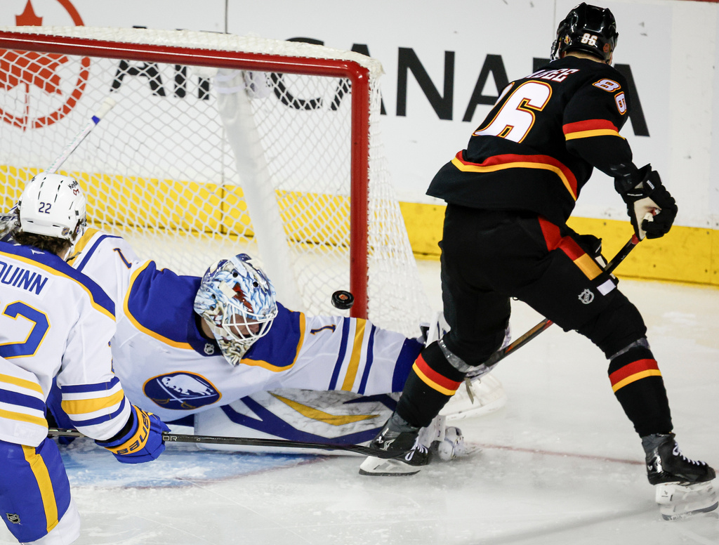 Buffalo Sabres' goalie Ukko-Pekka Luukkonen, left, makes a save on a shot from Calgary Flames' Joel Farabee during the second period of an NHL hockey game, in Calgary, Alberta, Monday, Dec. 8, 2025. (eff McIntosh/The Canadian Press via AP)