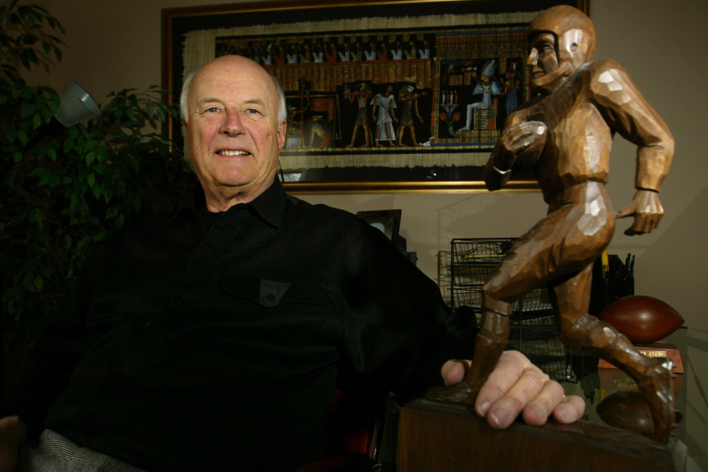 FILE - Chuck Neinas sits in his home office with an old football trophy, Feb. 27, 2003, in Boulder, Colo. (AP Photo/Jack Dempsey, File)