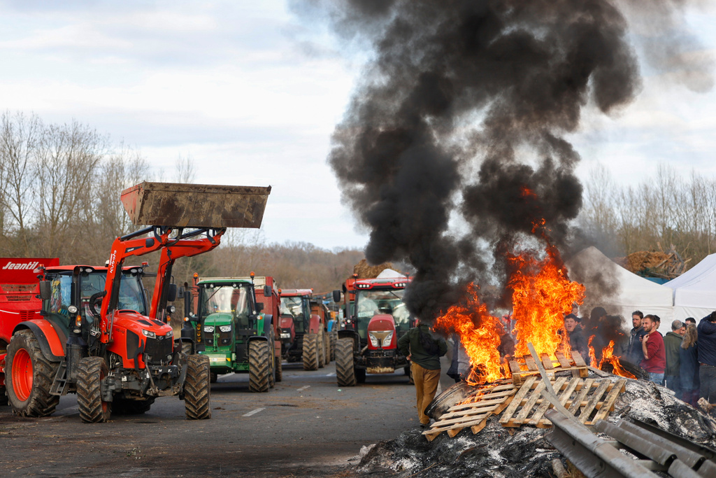 FILE - French farmers gather around a fire as they block the highway near Urt, southwestern France, to protest against a mass cull of cows ordered to contain the spread of a skin disease, Monday Dec. 15, 2025. (AP Photo/Nicolas Mollo, File)