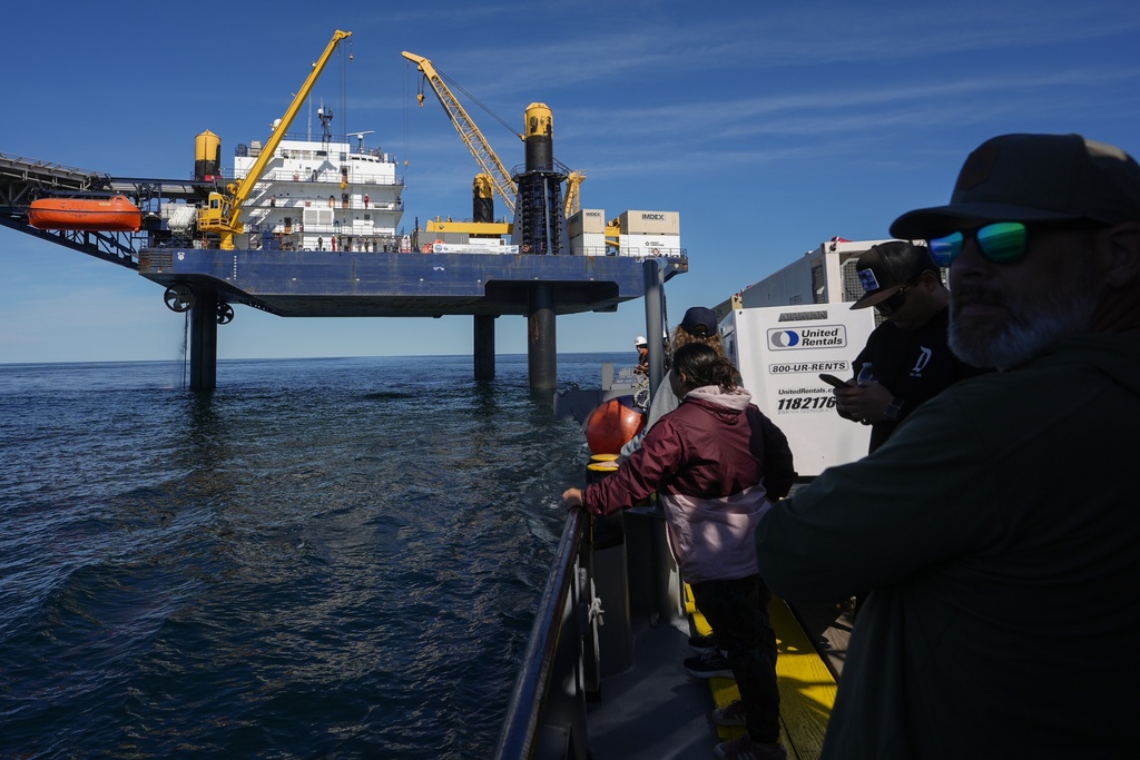 Expedition 501 members look down from the Liftboat Robert platform, to the approaching Gaspee, a crew transport vessel, in the North Atlantic, Saturday, July 19, 2025. (AP Photo/Carolyn Kaster)