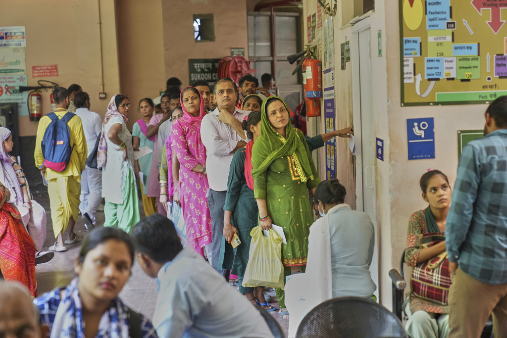Patients stand in a queue outside a doctor's room while they watch a Care Companion Program (CCP) session at a government hospital in Gurugram, a satellite city of New Delhi, India, on Aug. 7, 2025. (AP Photo/Manish Swarup)