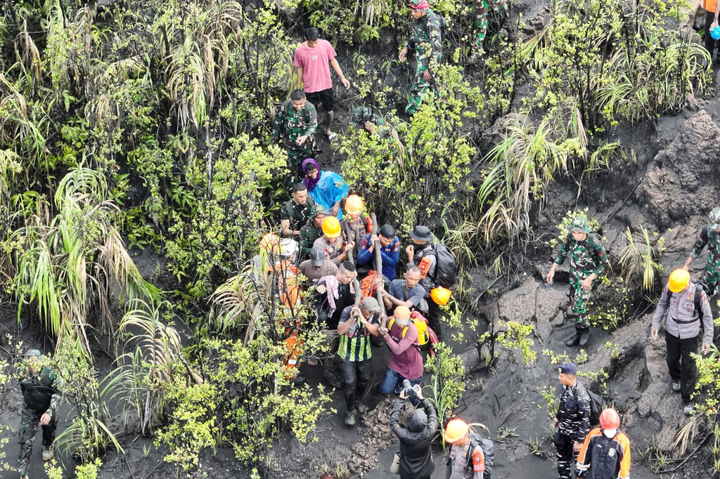 In this drone photo released by the Indonesian National Search and Rescue Agency (BASARNAS) rescuers carry the body of a victim of the eruption of Mount Dukono, on Halmahera Island, Indonesia, Saturday, May 9, 2026. (BASARNAS via AP)