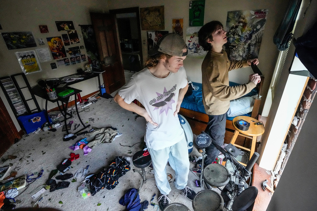 Quinn Ocker, left, and Aidan Bartlow work on installing a tarp over a blown our window in Ocker's bedroom after severe weather hit in the Memorial Northwest subdivision, in Spring, Texas, Monday, Nov. 24, 2025. (Brett Coomer/Houston Chronicle via AP)
