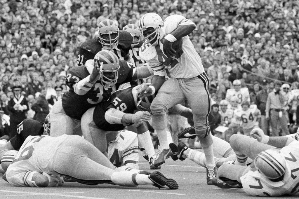 FILE - Ohio State's Archie Griffin picks up some of his game-high 163 yards against Michigan during an NCAA college football game in Ann Arbor, Mich., as Michigan's Walt Williamson (91), Carl Russ (33) and Steve Strinko (59) defend. (AP Photo/File)