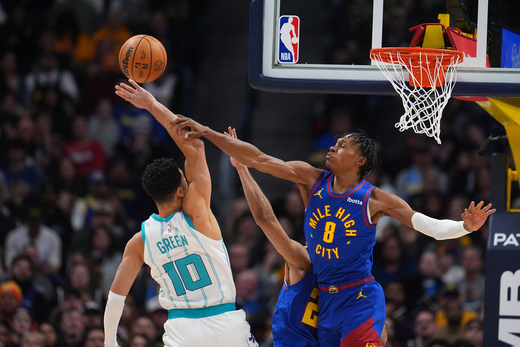 Denver Nuggets guard Peyton Watson, right, blocks a shot by Charlotte Hornets guard Josh Green, left, in the first half of an NBA basketball game Sunday, Jan. 18, 2026, in Denver. (AP Photo/David Zalubowski)