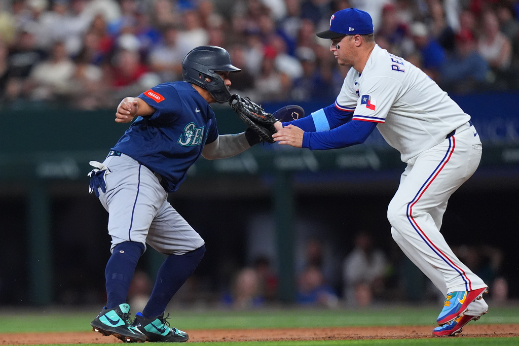 Seattle Mariners' Josh Naylor, left, is caught stealing second base on a rundown against Texas Rangers first baseman Joc Pederson during the second inning of a baseball game, Saturday, July 25, 2026, in Arlington, Texas. (AP Photo/LM Otero)