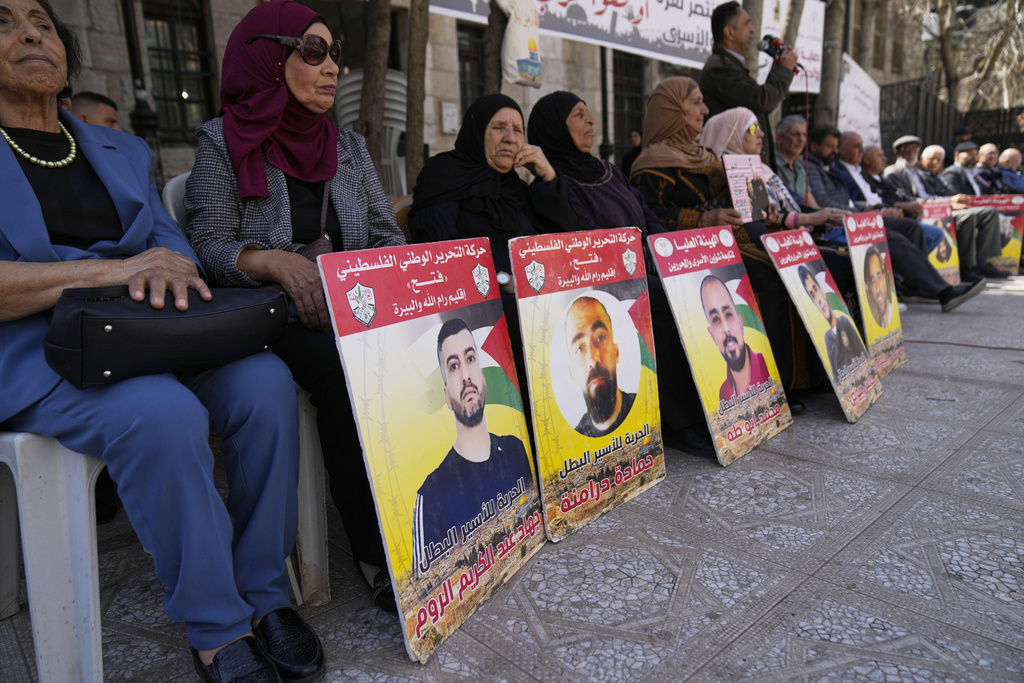FILE - People carry posters with pictures and names of Palestinian prisoners in Israel, one reads "freedom for the hero prisoner Hamada Daramnah," while protesting against the war in Gaza, in the West Bank city of Ramallah Tuesday, March 18, 2025. (AP Photo/Nasser Nasser,File)