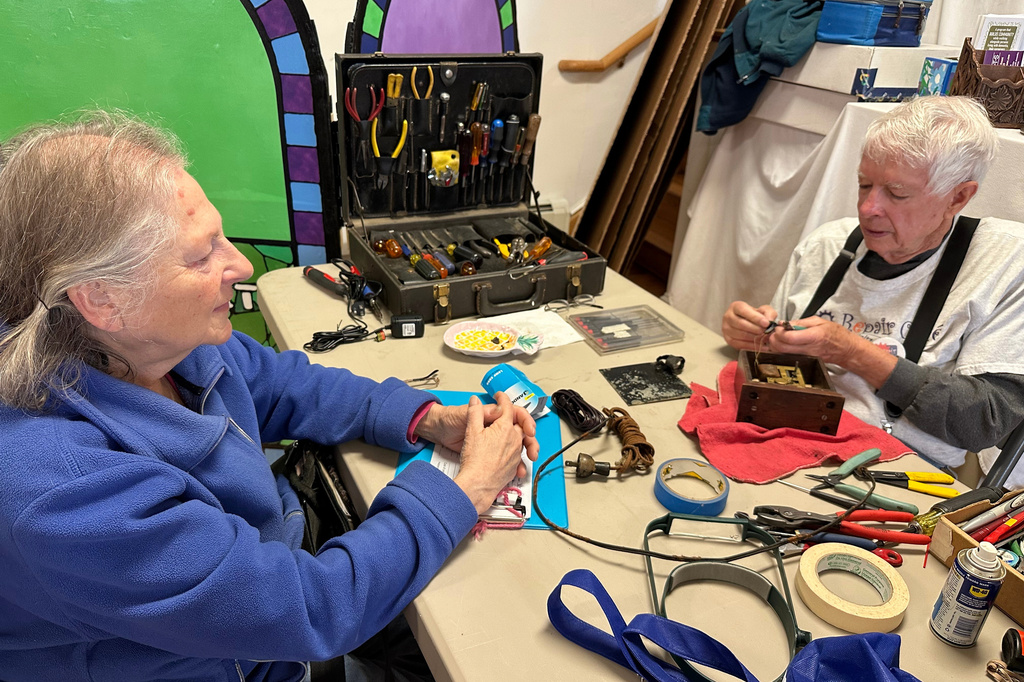 Bob Morton, a former IBM electrical engineer, right, repairs a 1930s-era Hammond clock for Paula Weinstein, at a Repair Café in New Paltz, N.Y., May 23, 2026. (AP Photo/Michael Weissenstein)