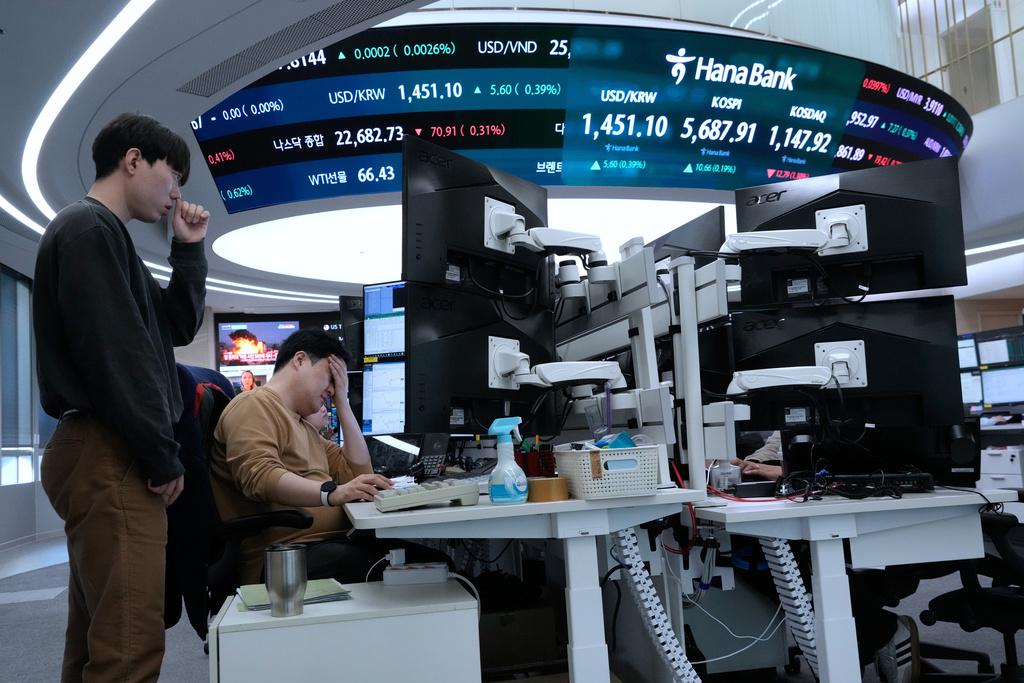 Currency traders work near a screen showing the Korea Composite Stock Price Index (KOSPI), top center, and the foreign exchange rate between U.S. dollar and South Korean won, top center left, at the foreign exchange dealing room of the Hana Bank headquarters in Seoul, South Korea, Friday, Feb. 20, 2026. (AP Photo/Ahn Young-joon)