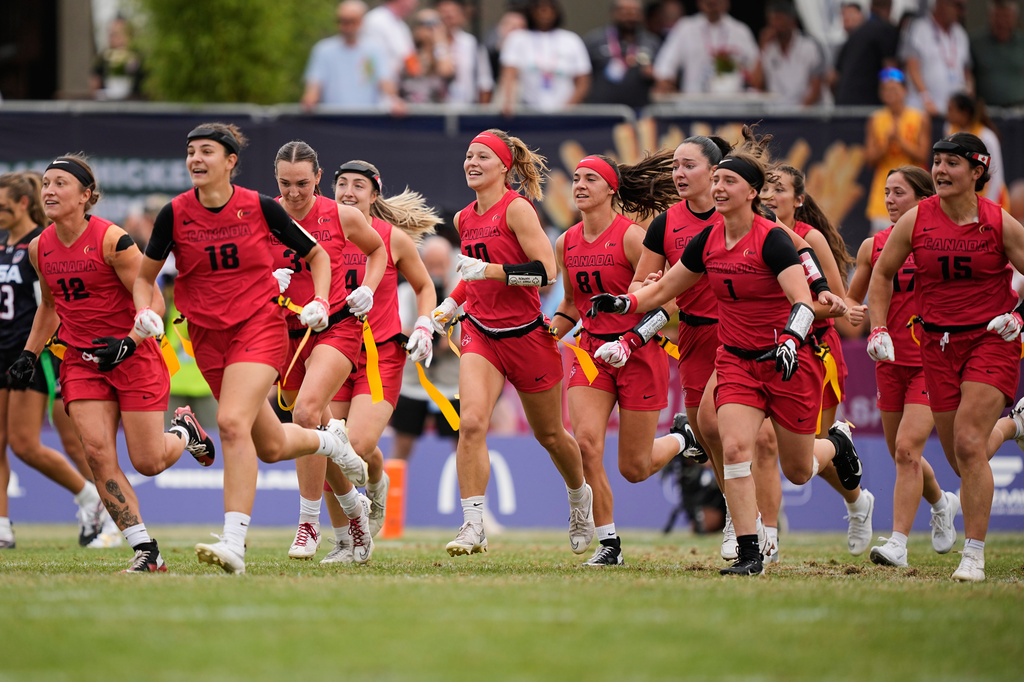 Canada's players celebrate and run to their injured teammate after winning the Flag Football World Championship women's final game between Canada and USA in Duesseldorf, Germany, Sunday, Aug. 16, 2026. (AP Photo/Martin Meissner)
