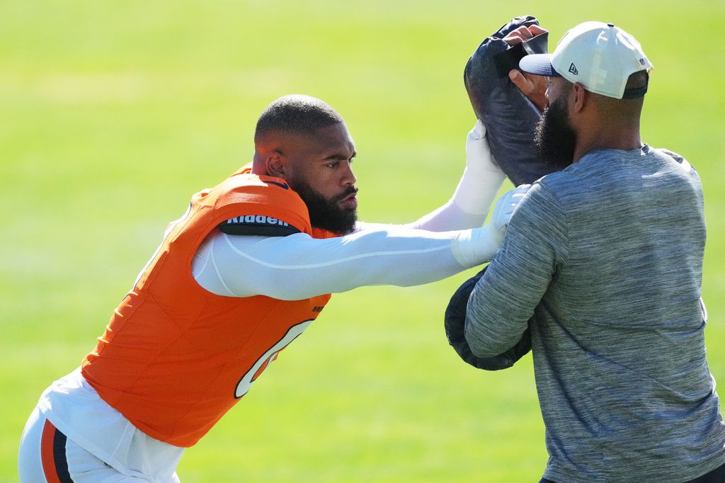 Denver Broncos linebacker Jonathon Cooper, left, takes part in drill with defensive assistant Michael Wilhoite during practice at the team's NFL football training camp Tuesday, Aug. 18, 2026, in Centennial, Colo. (AP Photo/David Zalubowski)