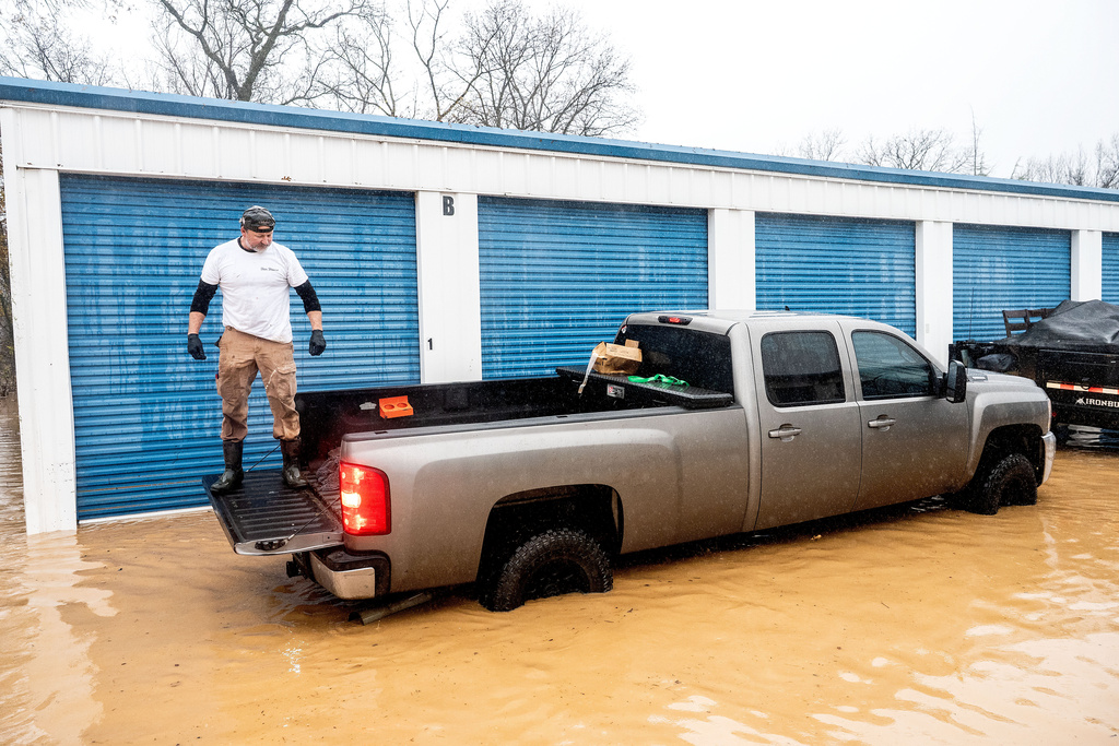 A man rides in a pick-up truck bed while salvaging belongings from a flooded storage unit following heavy rains on Monday, Dec. 22, 2025, in Redding, Calif. (AP Photo/Noah Berger)
