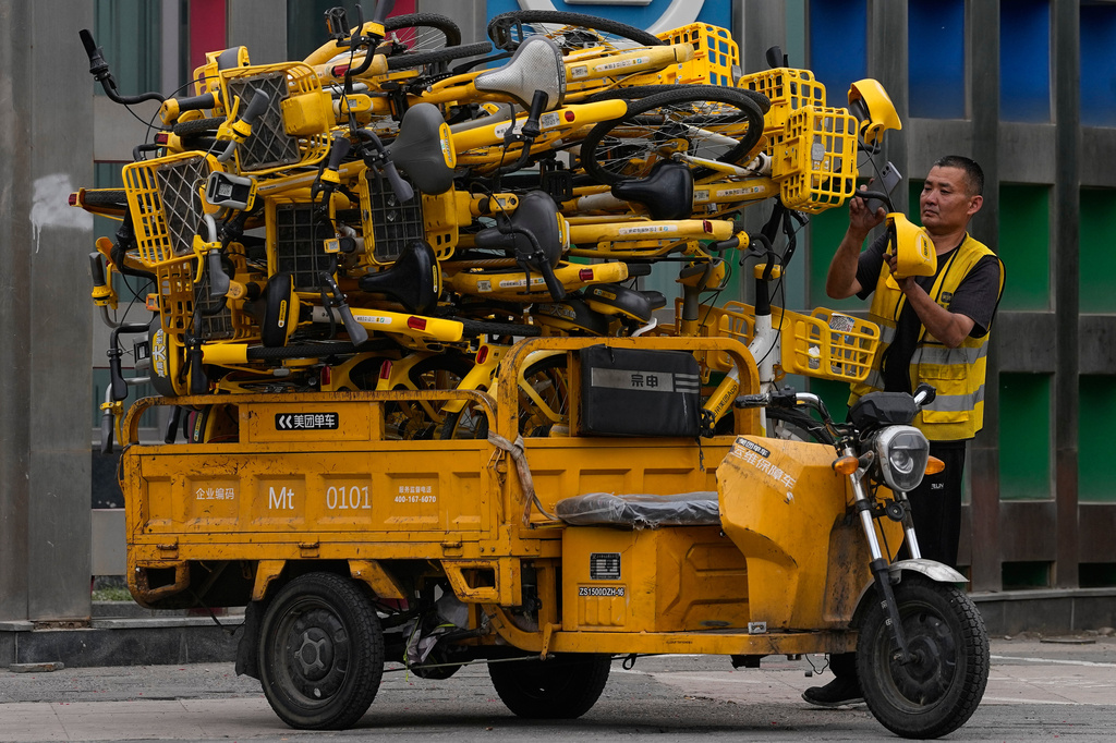 A worker scans the shared bicycles on his tricycle cart outside a subway station, in Beijing, China, Wednesday, May 6, 2026. (AP Photo/Andy Wong)