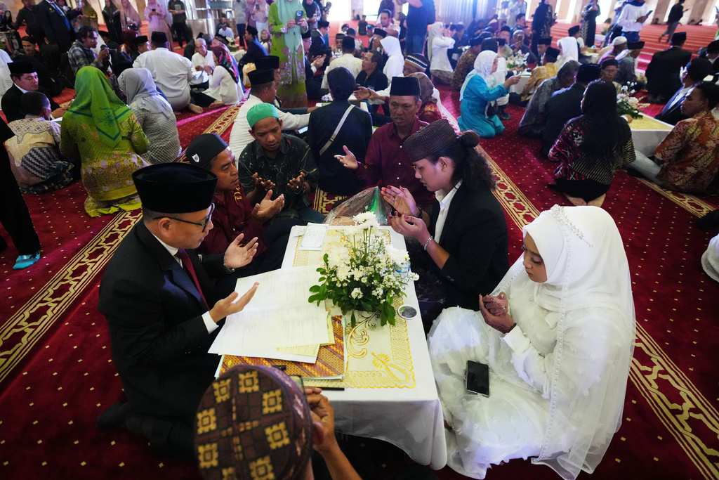 A bride and groom, right, pray after getting married during a mass wedding ceremony at Istiqlal Mosque in Jakarta, Indonesia, Wednesday, Dec. 3, 2025. (AP Photo/Tatan Syuflana)