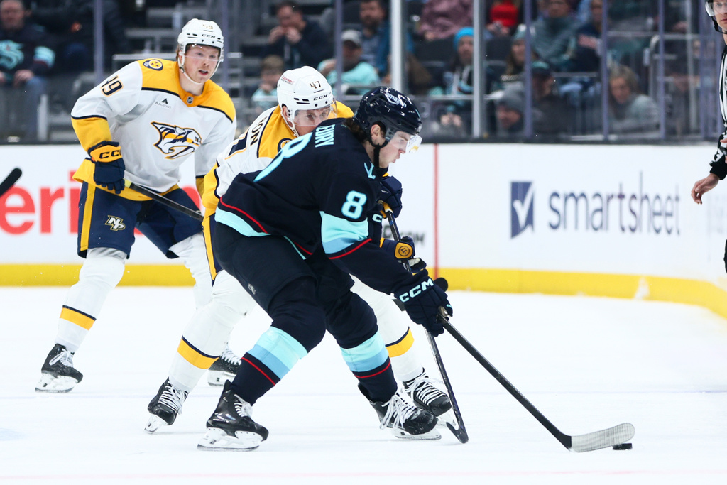 Seattle Kraken defenseman Cale Fleury (8) and Nashville Predators right wing Michael McCarron (47) battle for the puck in the second period during an NHL hockey game, Thursday, Jan. 1, 2026, in Seattle. (AP Photo/Kevin Ng)