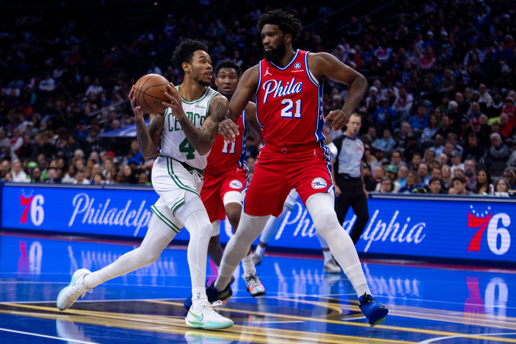 Boston Celtics' Anfernee Simons, left, drives to the basket against Philadelphia 76ers' Joel Embiid, right, during the first half of an NBA Cup basketball game, Friday, Oct. 31, 2025, in Philadelphia. (AP Photo/Chris Szagola)