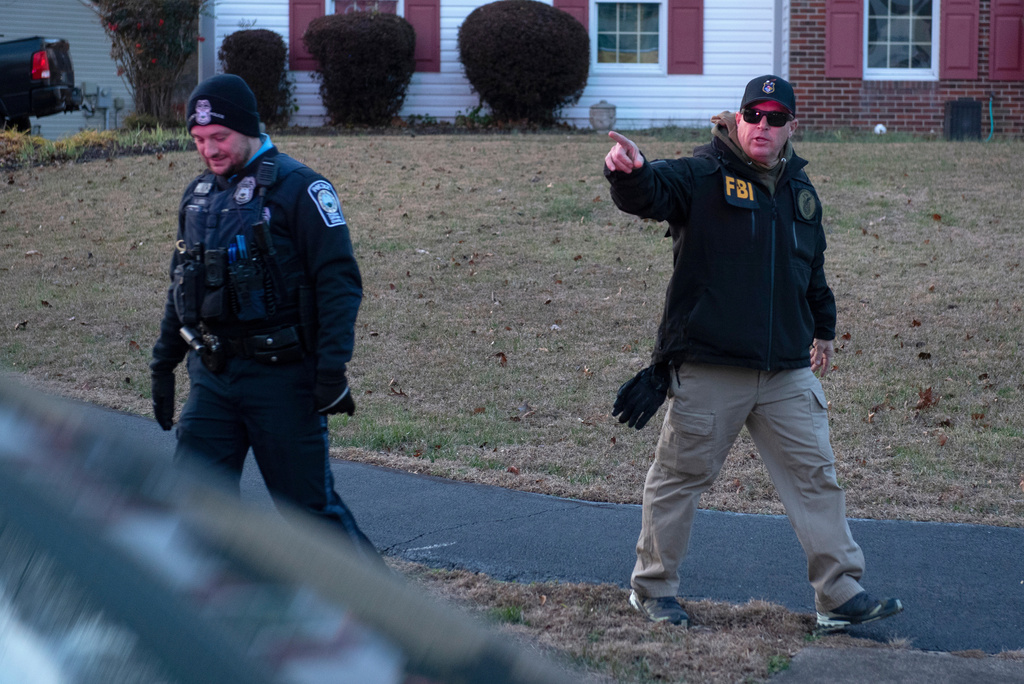 A FBI explosive ordnance agent talks with a Prince William County Police officers as agents investigate a house where the FBI made an arrest in Woodbridge, Va., Thursday, Dec. 4, 2025. (AP Photo/Cliff Owen)