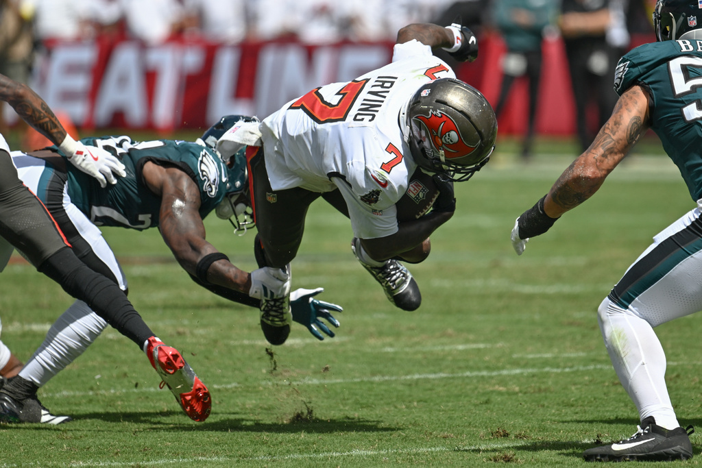 Tampa Bay Buccaneers running back Bucky Irving (7) is tripped up by Philadelphia Eagles safety Andrew Mukuba (24) during the first half of an NFL football game Sunday, Sept. 28, 2025, in Tampa, Fla. (AP Photo/Jason Behnken)