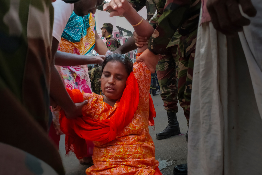 A family member faints near the site of a garment factory and chemical warehouse fire in Mirpur, Dhaka, Bangladesh, Tuesday, Oct. 14, 2025. (AP Photo/Mahmud Hossain Opu)
