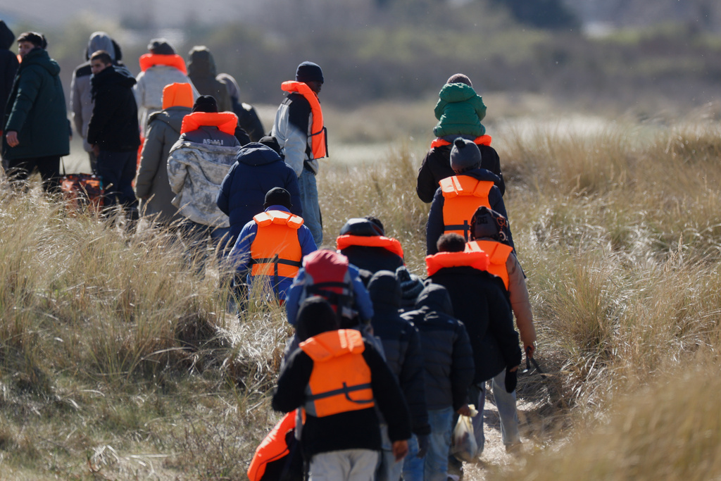 Migrants trying to reach Britain, walk on a beach shore in Gravelines, northern France, Wednesday, March 18, 2026. (AP Photo/Jean-Francois Badias)