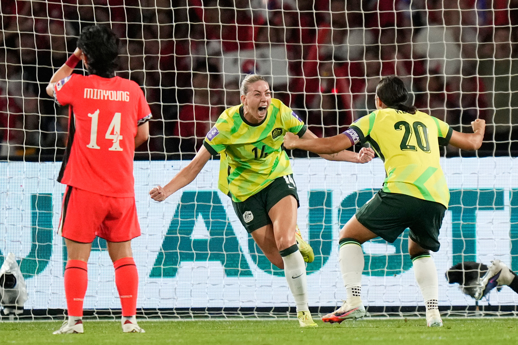 Australia's Alanna Kennedy, centre, celebrates with teammate Sam Kerr after scoring her team's first goal during the Women's Asian Cup soccer match between Australia and South Korea in Sydney, Sunday, March 8, 2026. (AP Photo/Rick Rycroft)