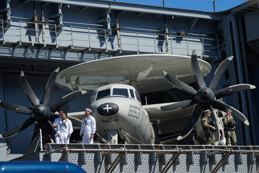 Sailors stand near a E-2 Hawkeye before President Donald Trump arrives to speak during a celebration for the 250th anniversary of the U.S. Navy aboard the USS Harry S. Truman at Naval Station Norfolk, Sunday Oct. 5, 2025 in Norfolk, Va. (AP Photo/Steve Helber)