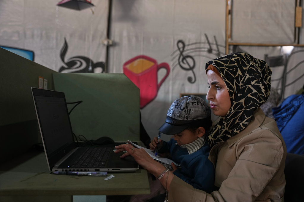 Palestinian graphic designer Reem Alkhateeb, 33, works on her computer next to her son at a coworking space in Khan Younis, southern Gaza Strip, March 9, 2026. (AP Photo/Abdel Kareem Hana)