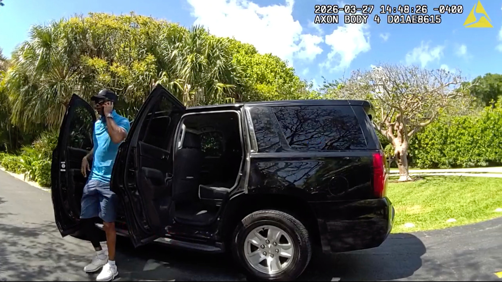 In this image from police body camera video released by the Martin County, Fla., Sheriff's Office, golfer Tiger Woods speaks on his cellphone as he steps out of an unmarked police vehicle following a car crash in Jupiter Island, Fla., Friday, March 27, 2026. (Martin County Sheriff's Office via AP)