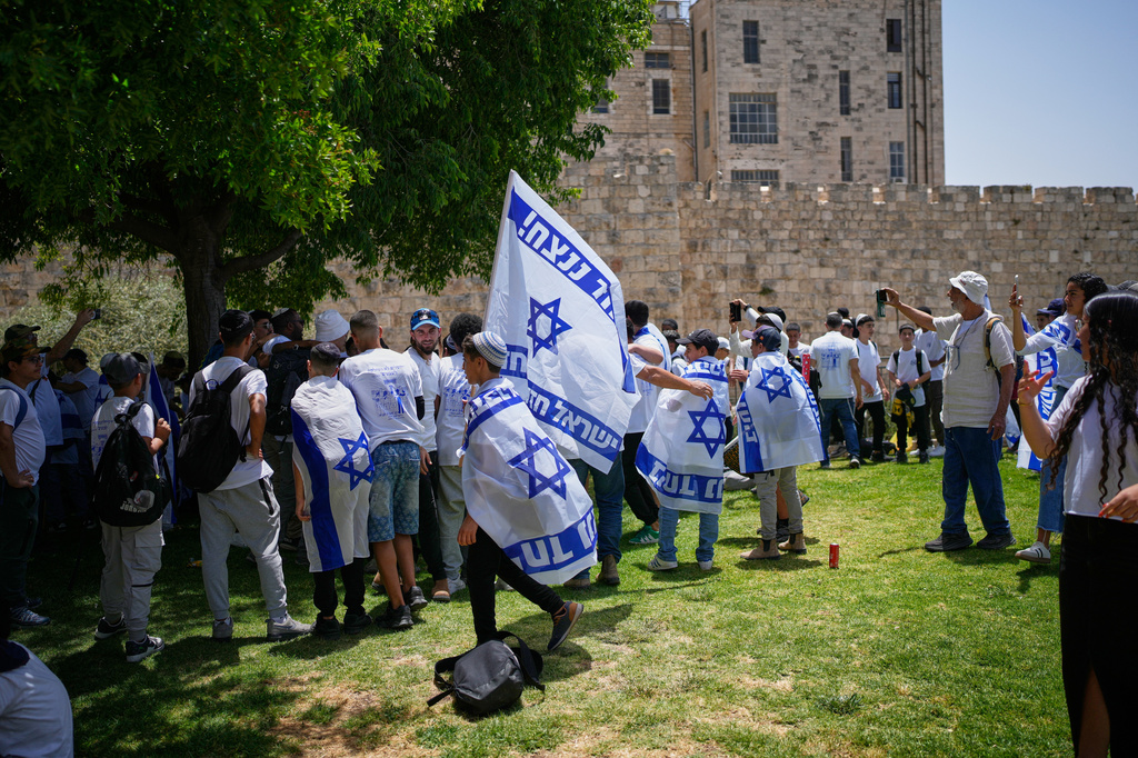 Israeli youth carrying Israeli flags gather outside Jerusalem's Old City walls before a march marking Jerusalem Day, an Israeli holiday celebrating the capture of east Jerusalem in the 1967 Mideast war, in Jerusalem, Thursday, May 14, 2026. The writing on the flags reads in Hebrew: "Together we will win. Israel is united and strong." (AP Photo/Ohad Zwigenberg)
