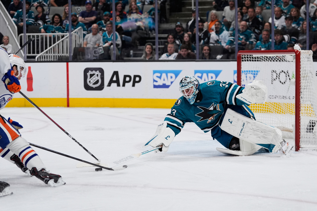 San Jose Sharks goaltender Alex Nedeljkovic (33) is unable to knock the puck away from Edmonton Oilers center Connor McDavid, left, during the second period of an NHL hockey game, Wednesday, April 8, 2026, in San Jose, Calif. (AP Photo/Godofredo A. Vásquez)