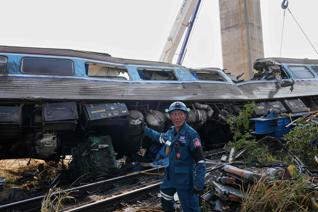 A rescuer stands near the wreckage after a construction crane fell into a passenger train in Nakhon Ratchasima province, Thailand, Wednesday, Jan.14, 2026. (AP Photo/Sakchai Lalit))