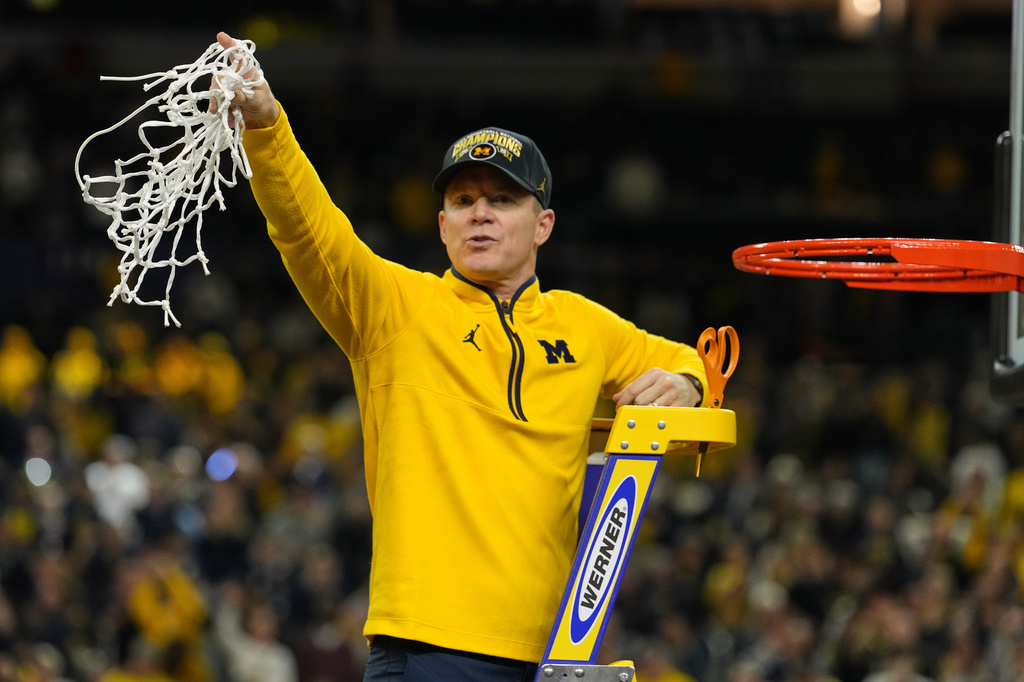 Michigan head coach Dusty May celebrates by cutting down the net after defeating UConn in the NCAA college basketball tournament national championship game at the Final Four, Monday, April 6, 2026, in Indianapolis. (AP Photo/Michael Conroy)