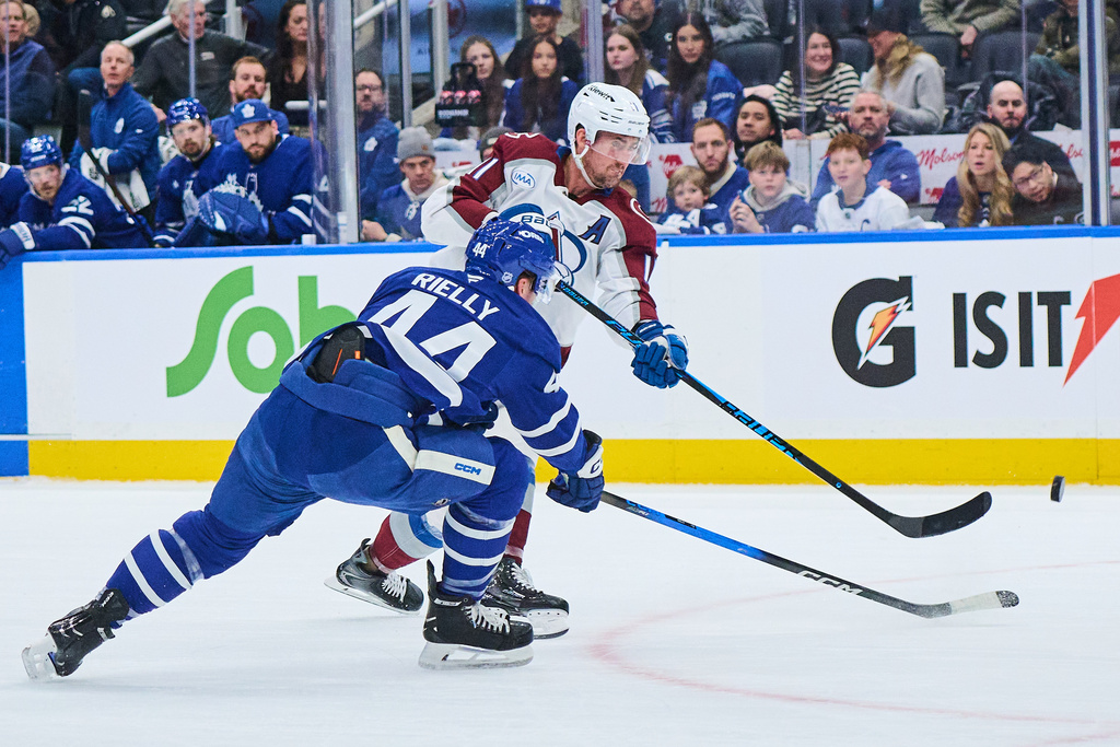 Colorado Avalanche's Brock Nelson (11) shoots past Toronto Maple Leafs' Morgan Rielly (44) during the first period of an NHL hockey game in Toronto, on Sunday, Jan. 25, 2026. (Sammy Kogan/The Canadian Press via AP)