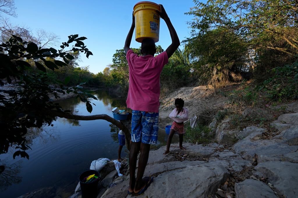 FILE - Children carry water from the Branco River at dawn at the Kalunga quilombo, a Brazilian settlement founded by escaped enslaved Africans, in the rural area of Cavalcante in Goias state, Brazil, Aug. 15, 2022. (AP Photo/Eraldo Peres, File)