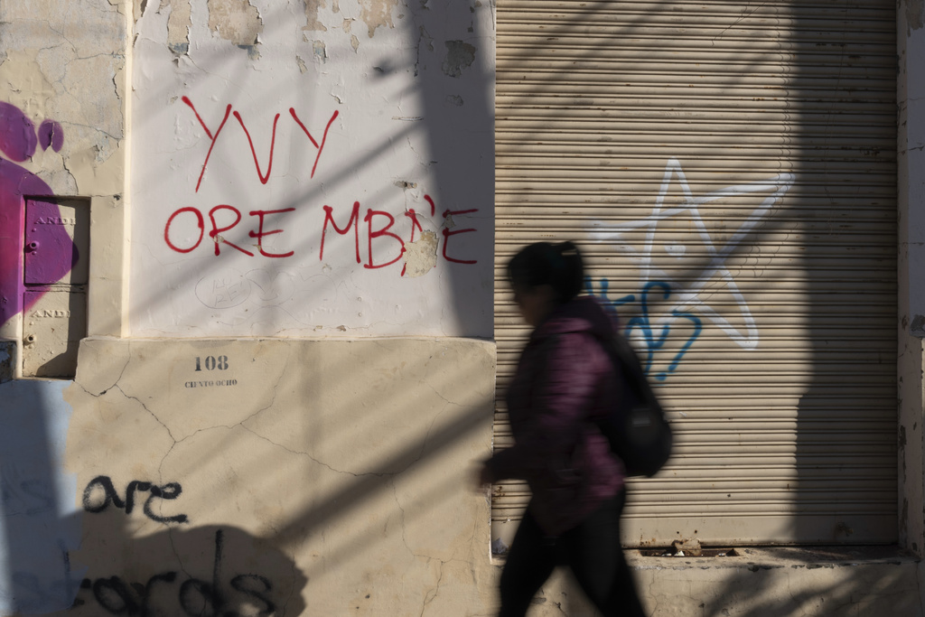 A pedestrian passes graffiti that reads in the Guarani languaje "yvy ore mba'e" which means "The land is ours" in Asuncion, Friday, Aug. 22, 2025. (AP Photo/Jorge Saenz)