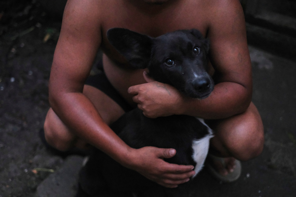 Tovi Murru, 32, puts his arms around his pet dog outside his house in Kohima, capital of the northeastern Indian state of Nagaland, Monday, July 6, 2026. (AP Photo/Yirmiyan Arthur)