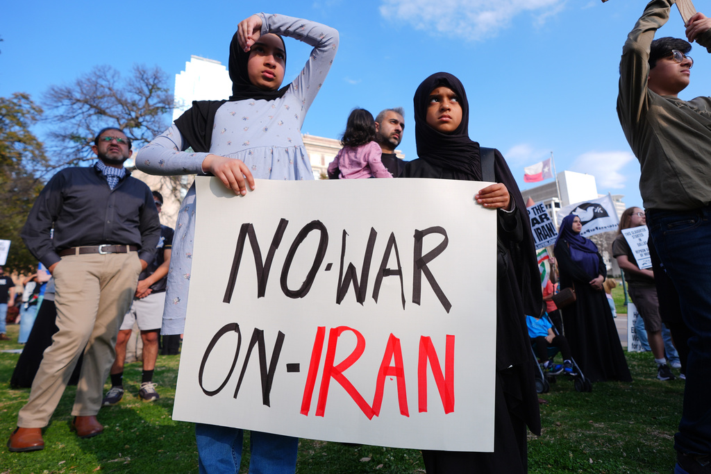 Children hold a sign protesting war against Iran during an antiwar demonstration at Dealey Plaza in downtown Dallas, Sunday, March 1, 2026. (AP Photo/LM Otero)