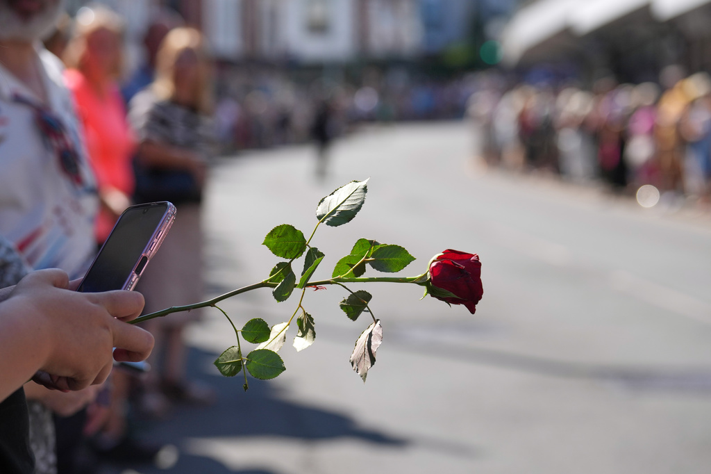 Fans of singer Bonnie Tyler line the streets as they await the coffin to be transported back to her former home ahead of the funeral in Mumbles, Wales, Saturday, Aug. 15, 2026. The Total Eclipse Of The Heart musician, whose real name was Gaynor Hopkins, died in hospital in Portugal on July 8 at the age of 75. (AP Photo/Alastair Grant)