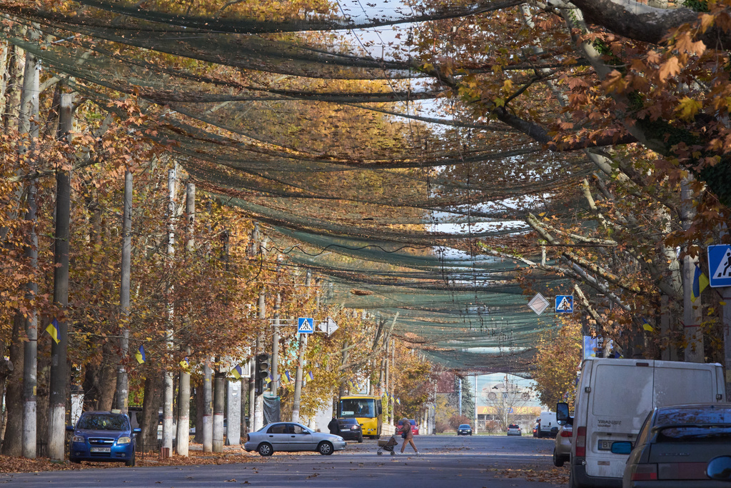 Local residents go along the street covered with an anti-FPV-drone net in the frontline city of Kherson, Southern Ukraine, Nov. 3, 2025. (AP Photo/Efrem Lukatsky)